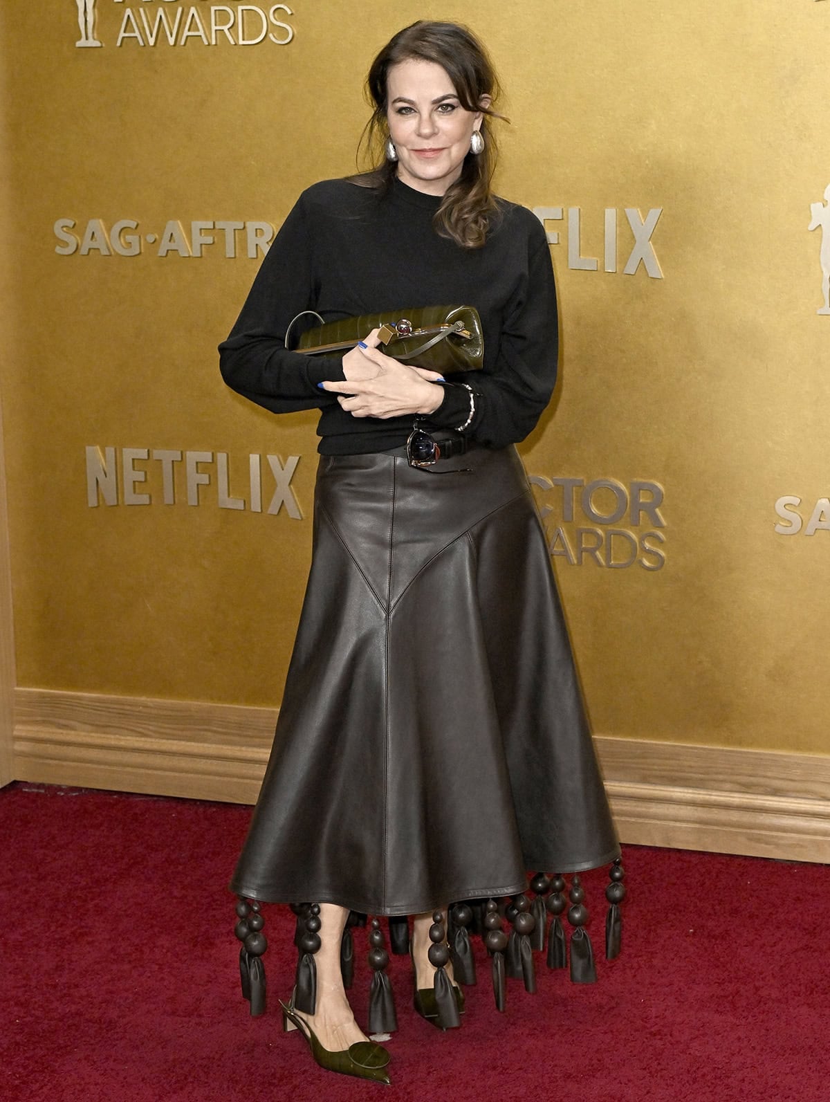 Francine Maisler pairs her geometric shoes with a brown leather Jacquemus “The Triangle” A-line midi skirt with oversized leather-covered balls and long leather tassels