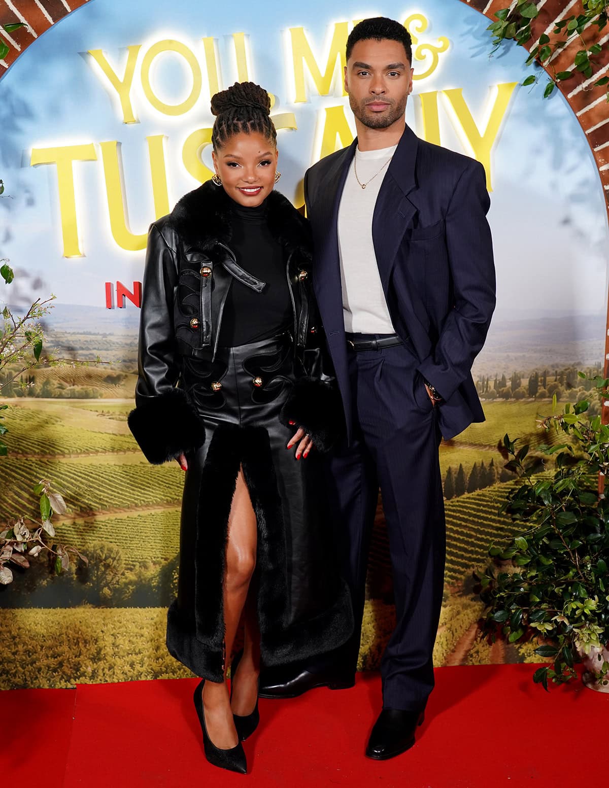 Halle Bailey stuns in a fur-trimmed Raisa Vanessa leather ensemble with sleek black Casadei pumps as she poses beside Regé-Jean Page at the UK special screening of You, Me & Tuscany