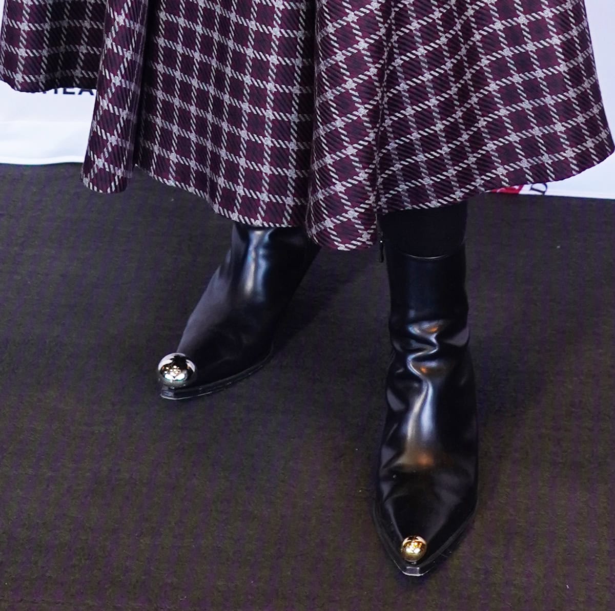 Hayley Atwell grounds her Emilia Wickstead look with A.W.A.K.E. Mode’s “Gabriel” boots—sleek black leather ankle boots featuring sharply squared pointed toes and mismatched metal baubles (silver on one, gold on the other), adding a subtle Western edge