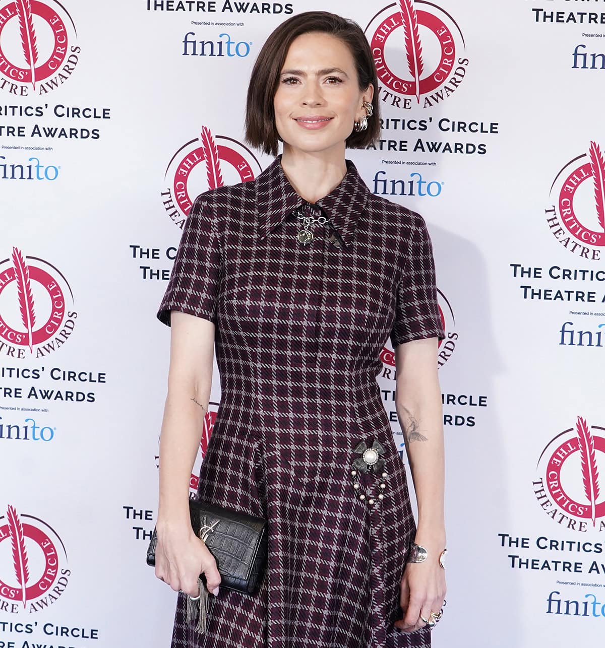 Hayley Atwell adds sparkles to her look with multiple thick hoop earrings, rings, a wide cuff, and a YSL clutch with a chain tassel