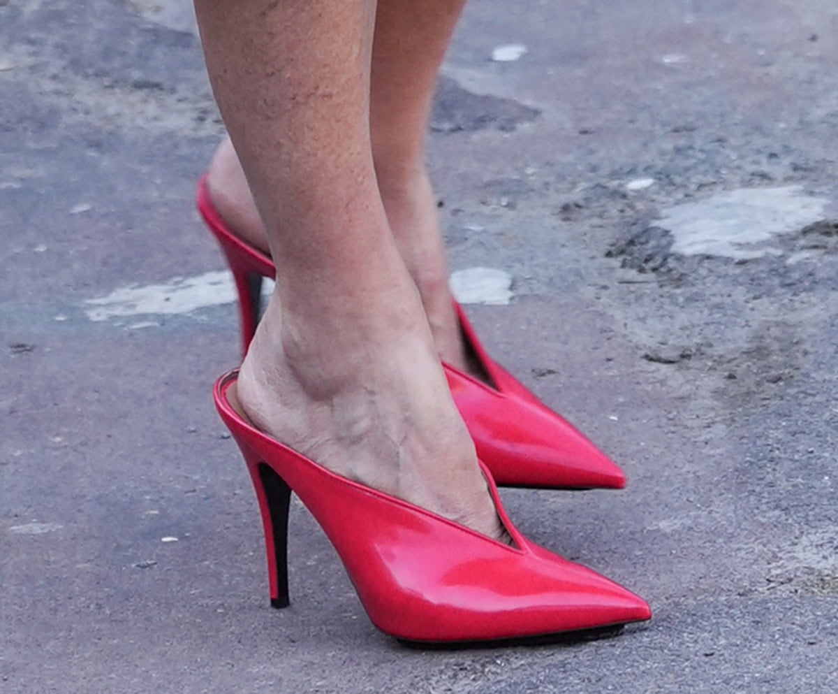 Helen Hunt adds color to her neutral ensemble with the Stella McCartney red mules featuring a V-cut vamp, pointed toes, and high heels