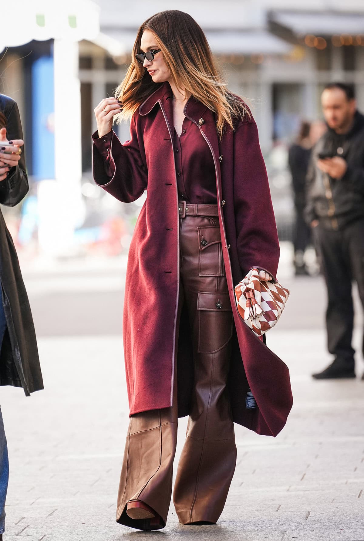 Lily James pairs the brown platform sandals with brown leather Zimmermann “Luna” pants, a wine red “Luna” silk satin relaxed shirt, and a matching wool wrap coat