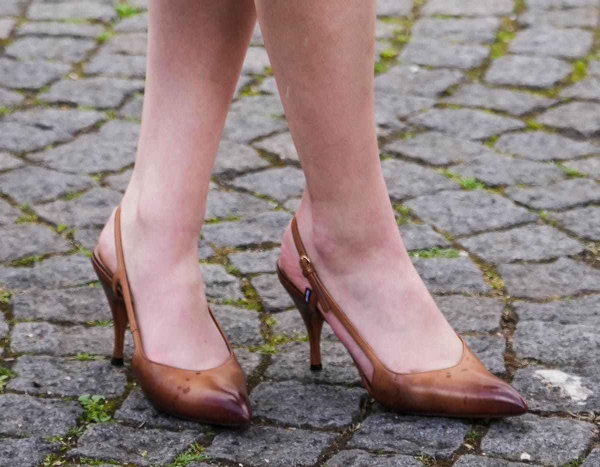 Lola Tung wears the cognac, slingback version of the hand-waxed pumps with side cutouts, pointed toes, and heels