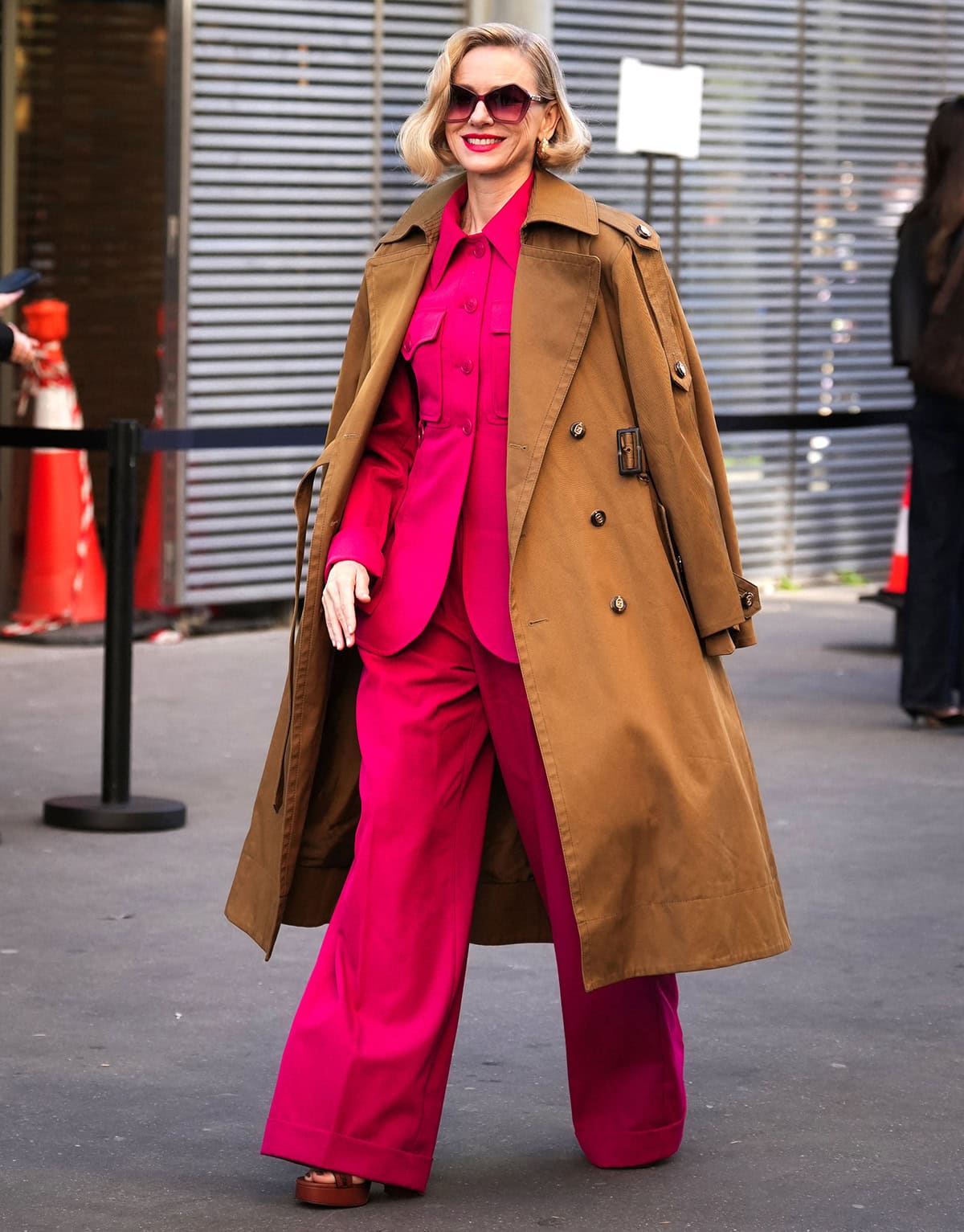 Naomi Watts pairs her brown platform sandals with a pink tailored set from Zimmermann, featuring the “Luna” longline wool-blend blazer and matching pants, and a camel coat