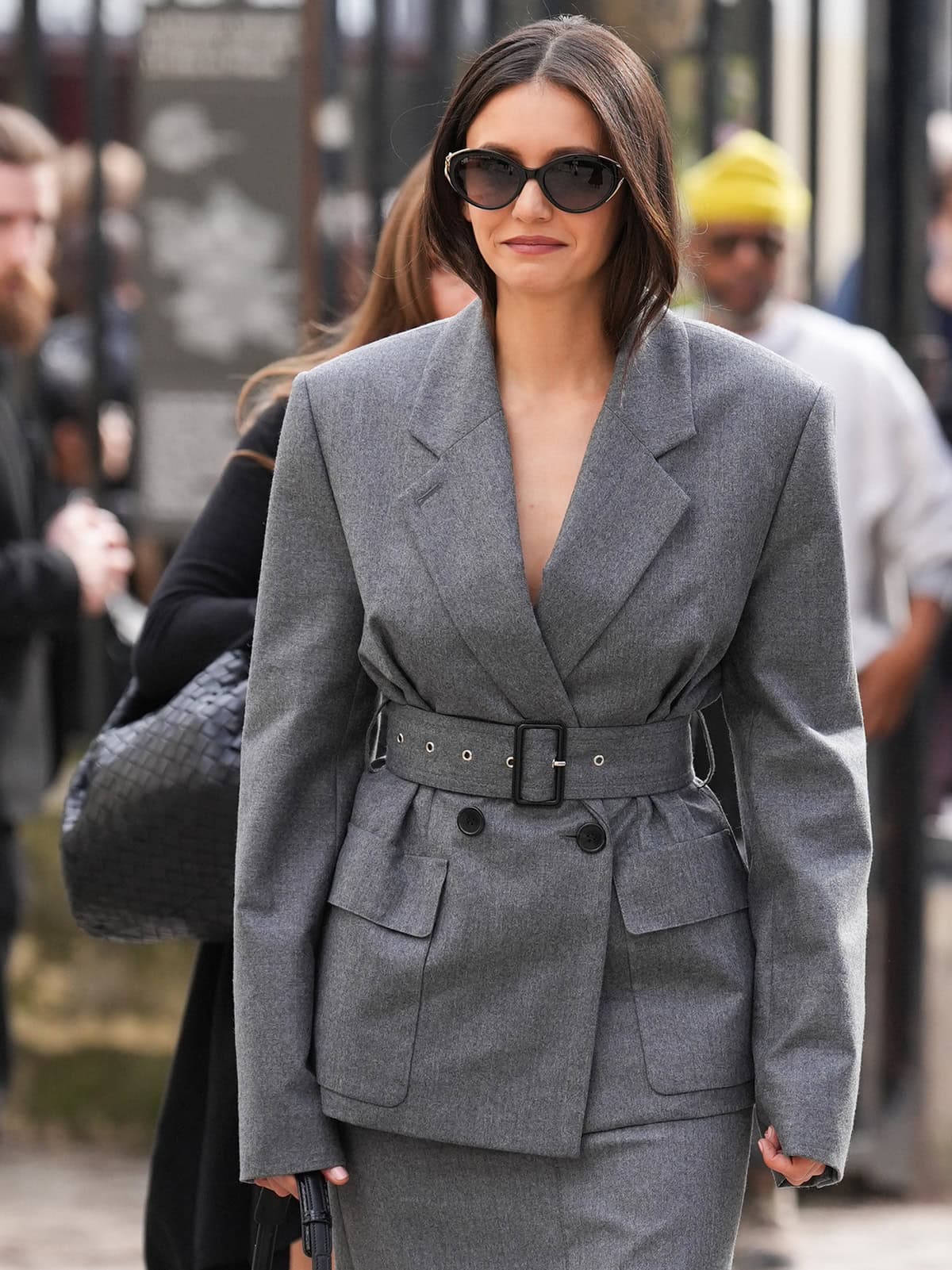 Nina Dobrev adds star power to her gray tailoring with semi-oval Lanvin sunglasses, mauve lipstick, and a Lanvin “Compagnon” bag