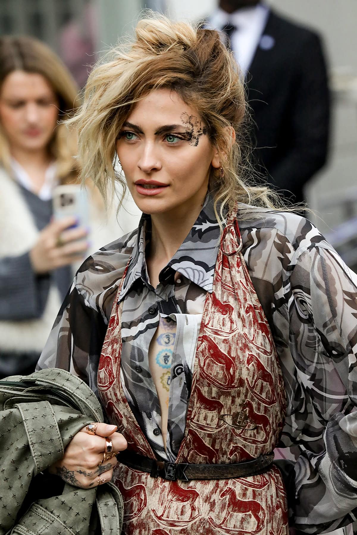 Paris Jackson pairs her black leather boots with a red horse-printed catsuit and a gray swirl-patterned maxi blouse