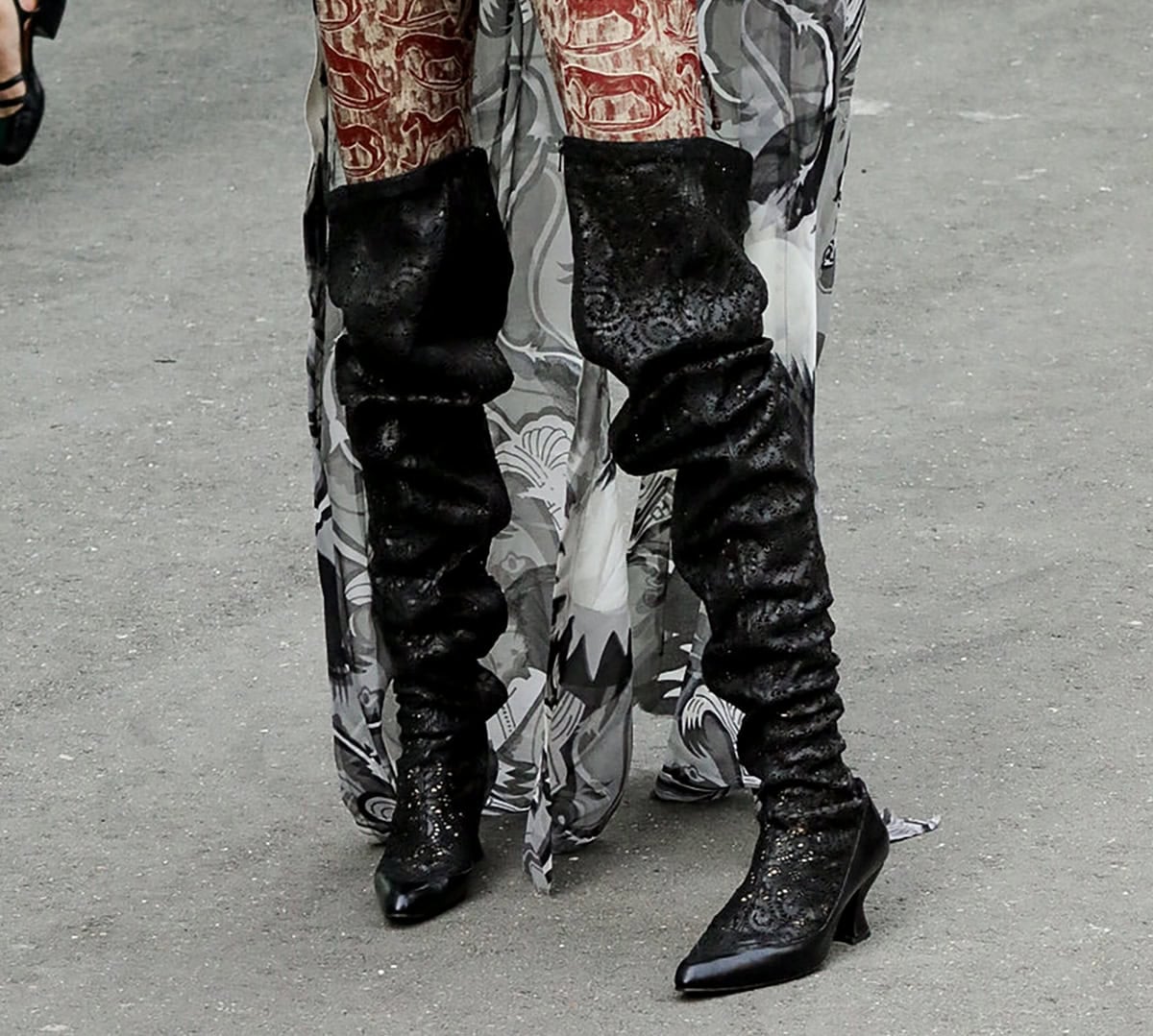 Paris Jackson slips into a pair of black leather over-the-knee boots with swirling eyelet cutouts all over, slouchy shafts, pointed toes, and French heels