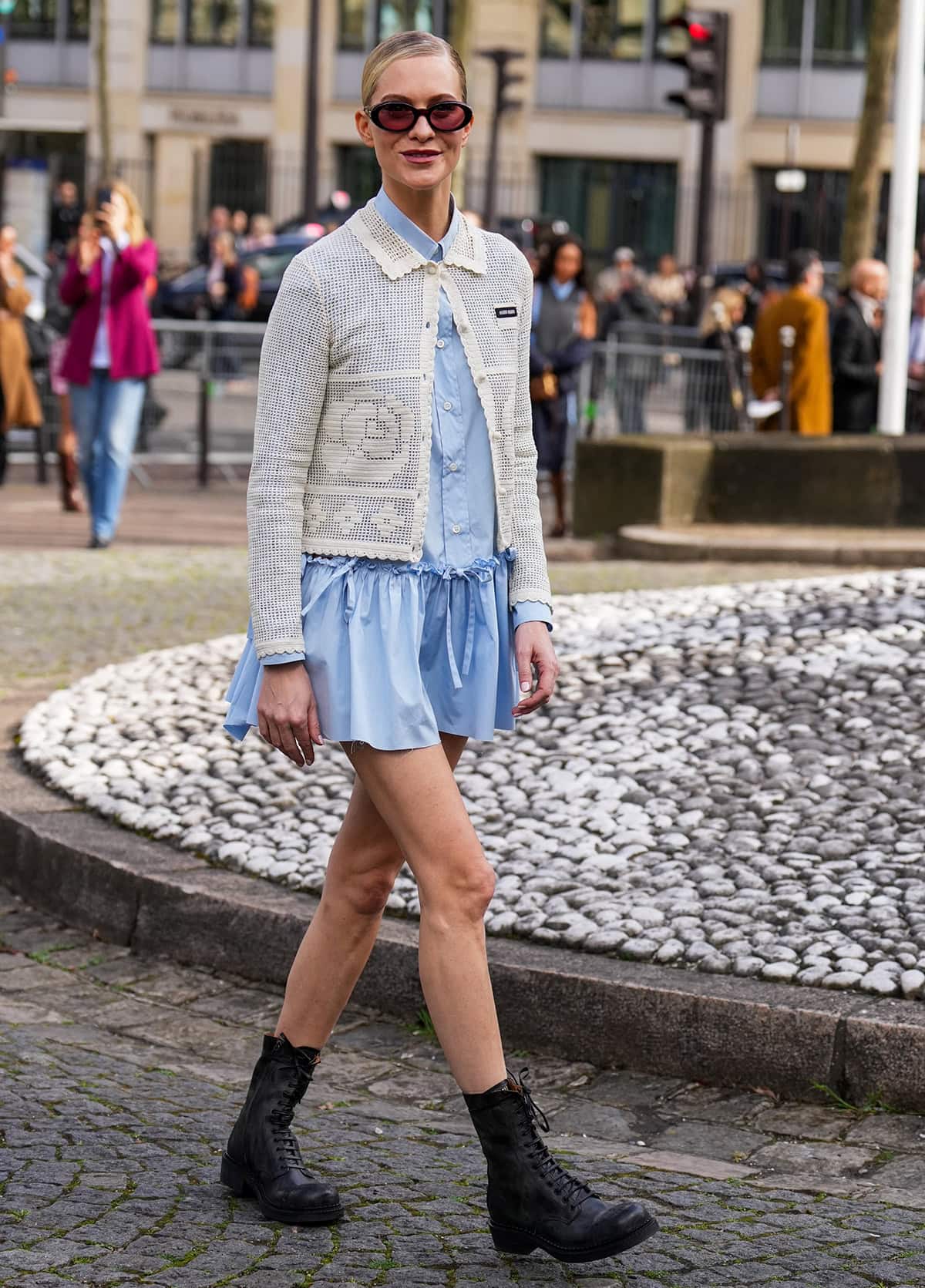 Poppy Delevingne pairs her rugged black lace-up boots with a blue mini dress and a white crochet cardigan