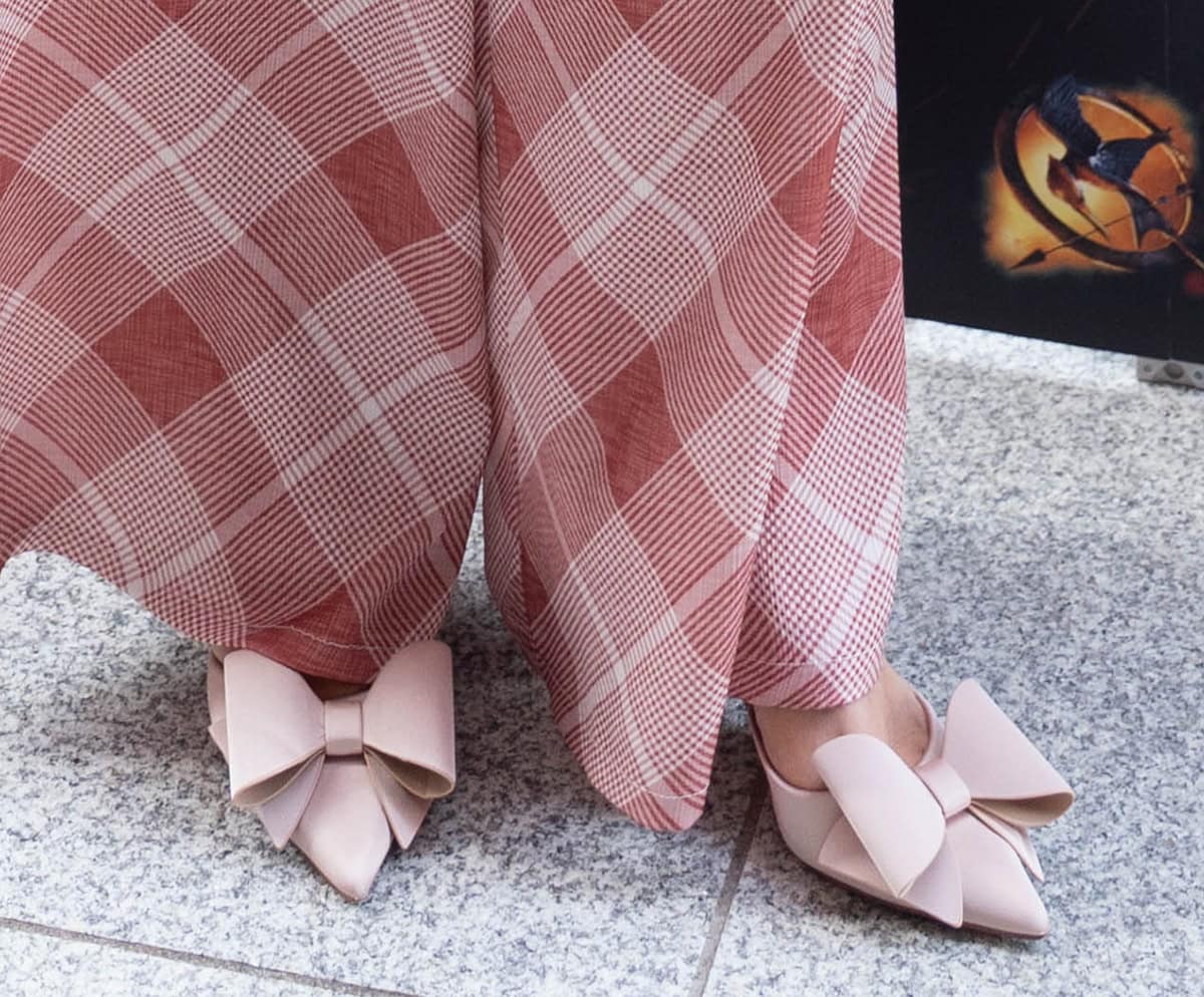 Rachel Duffy slips into a pair of feminine blush pink mules with pointed toes, a slim strap across the foot, and a large structured bow
