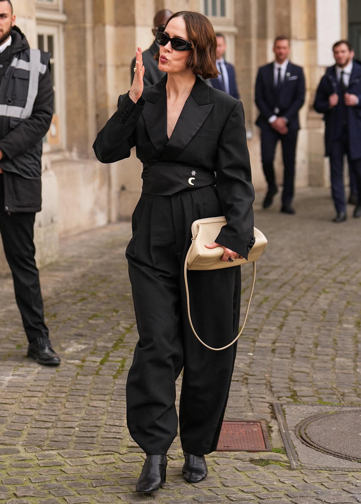 Sarah Paulson completes her sleek, monochromatic black look with a black jumpsuit featuring a tuxedo-style top and balloon-like pants with satin side stripes