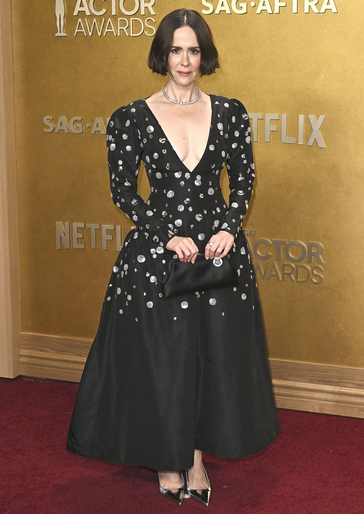 Sarah Paulson wears a vintage Yves Saint Laurent dress from the Fall 1979 collection, featuring a silver polka dot pattern, long sleeves, a plunging neckline, and a voluminous skirt