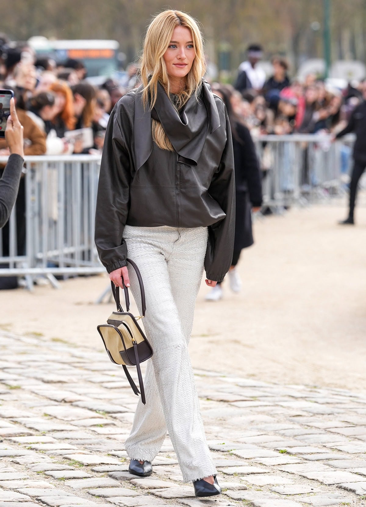 Sarah Pidgeon pairs her sleek V-neck pumps with white frayed pants and an oversized draped black leather jacket