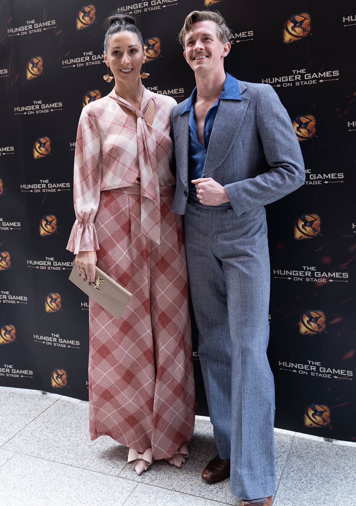 Rachel Duffy, with her fellow The Traitors Season 4 winner Stephen Libby, looks feminine and chic in a salmon pink plaid top with a pussy bow scarf and matching wide-leg pants