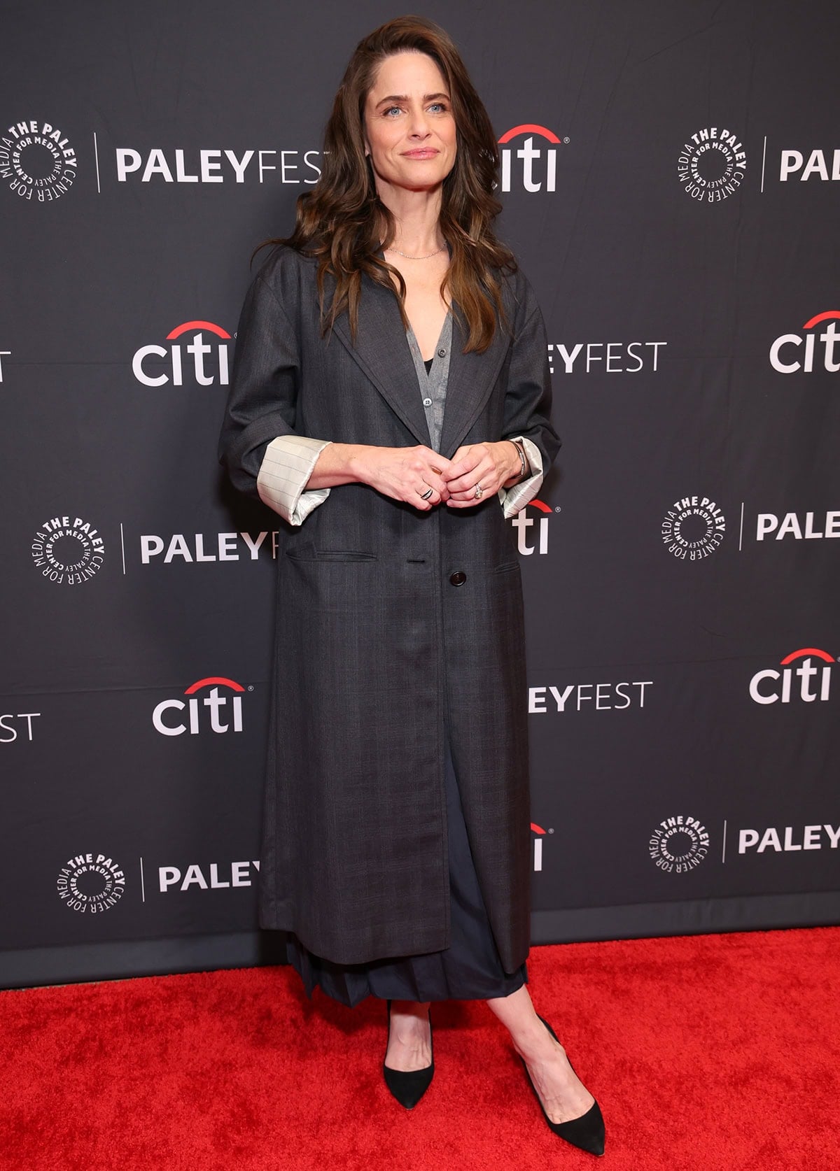 Amanda Peet leans into understated elegance with a layered Prada coat and pointed black suede pumps that add quiet structure and polish to her relaxed silhouette