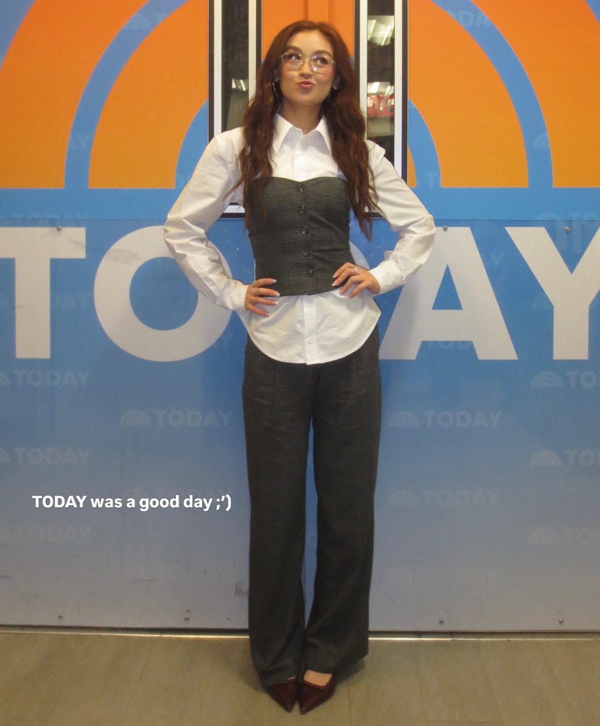 Anna Cathcart sharpens her Today show look with a crisp white shirt layered under a tailored gray plaid Aniye By corset and matching trousers, grounded by pointed burgundy slingback pumps that add a refined pop of color
