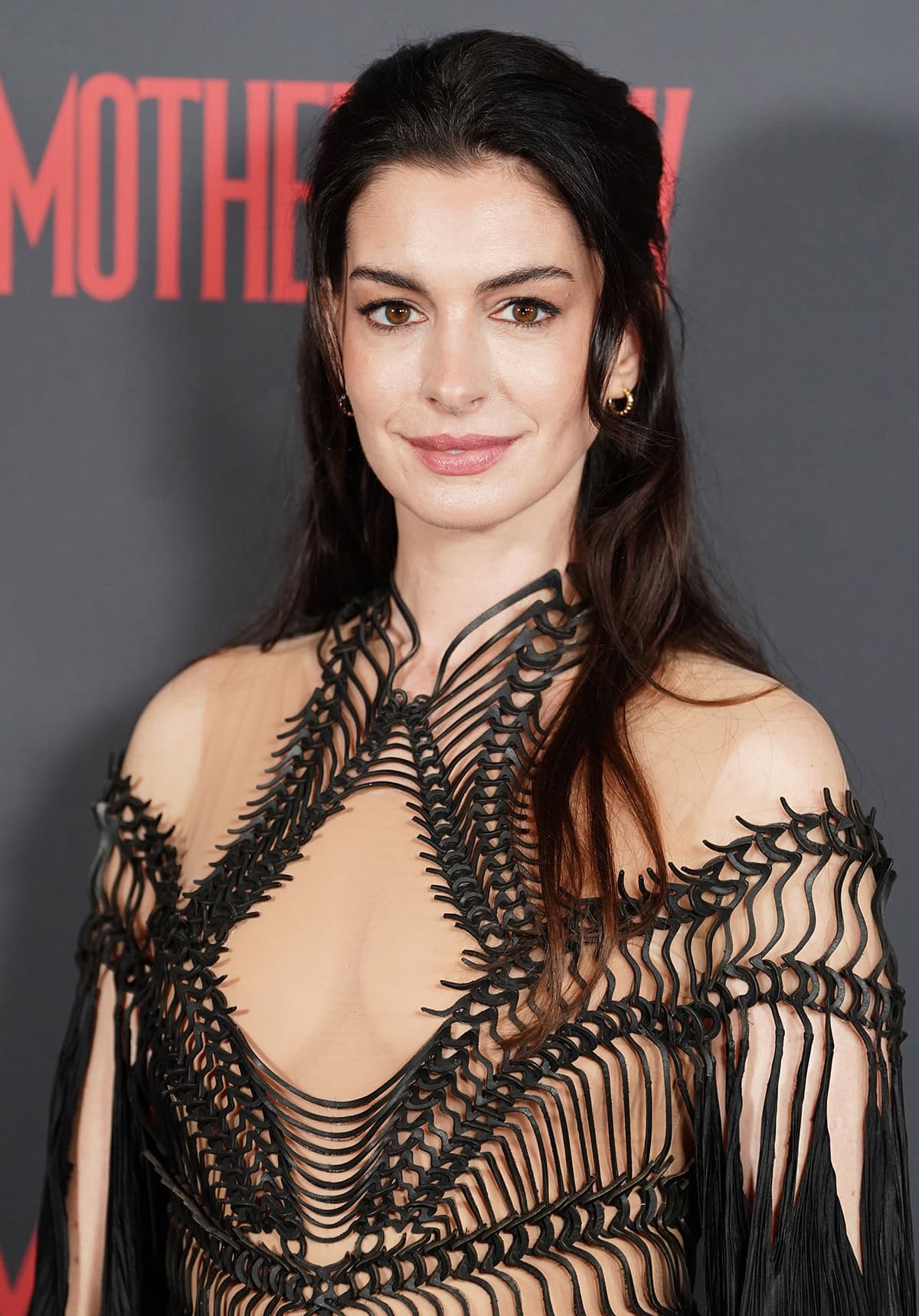Anne Hathaway keeps the gothic vibe going by wearing eyeliner, styling her hair down in loose waves, and wearing minimal jewelry