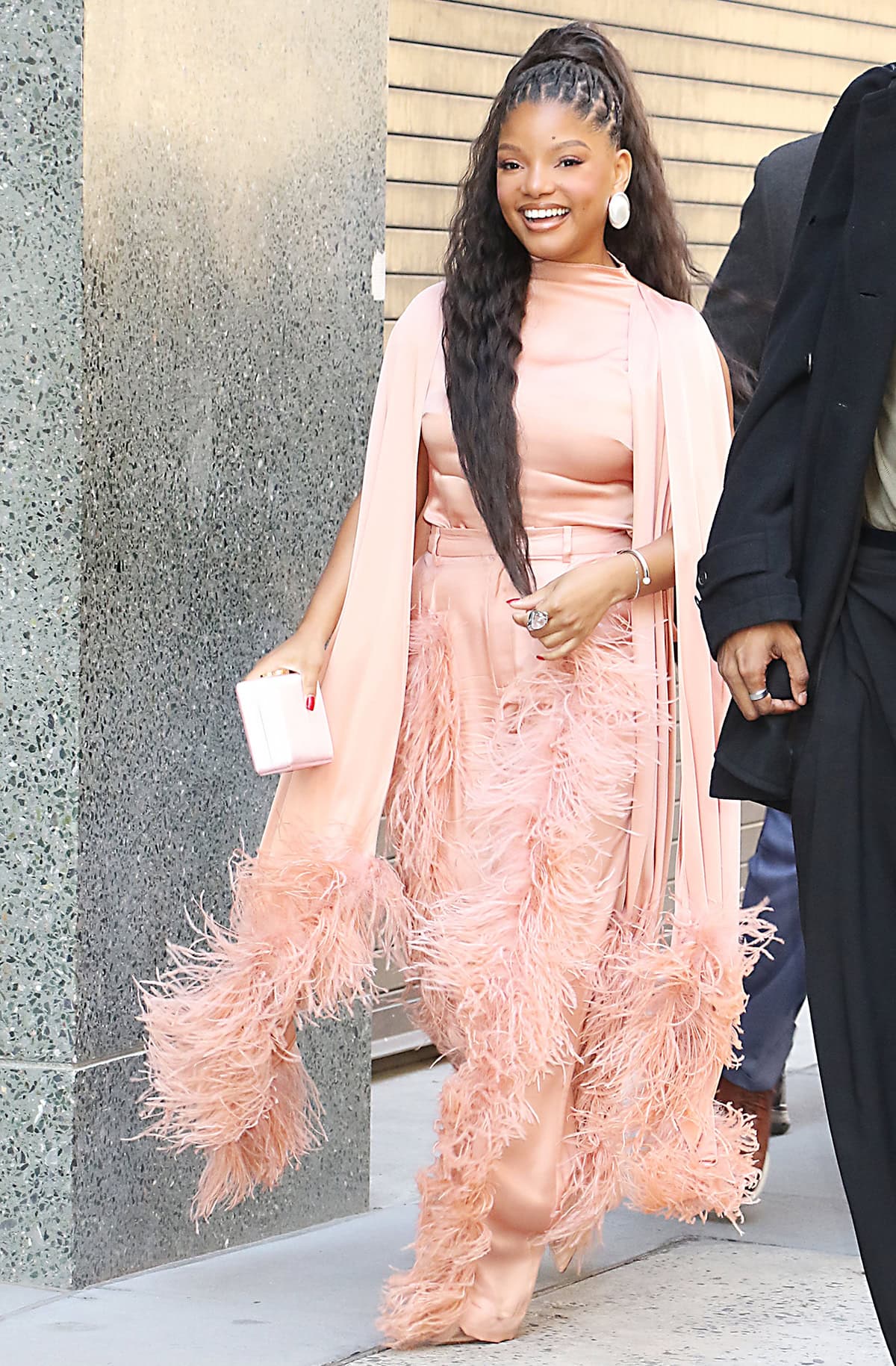 Halle Bailey pairs her mesh pumps with a peachy LaPointe ensemble featuring a feathered cape dress and matching high-waisted pants with feather trims