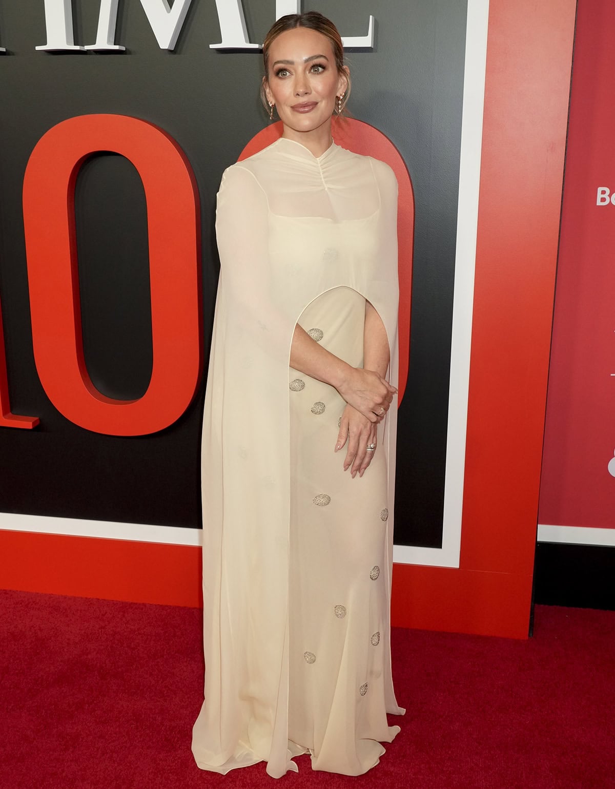 Hilary Duff teams her barely there sandals with a semi-sheer pale daffodil silk column dress with moonlight bead motifs and a matching sheer cape by Anna October
