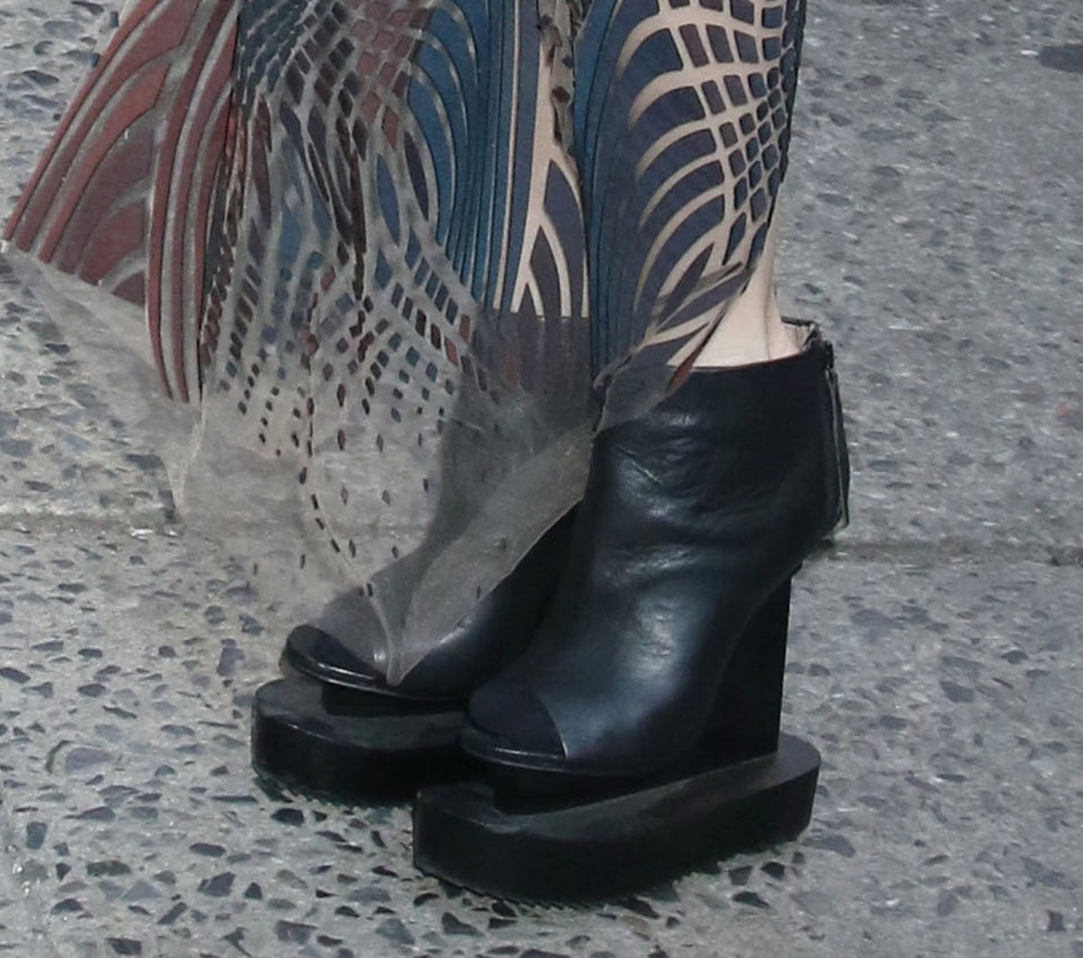 Iris van Herpen slips into a pair of boots from her own collection, featuring wooden platforms, an offset wedge, peep toes, and side zips