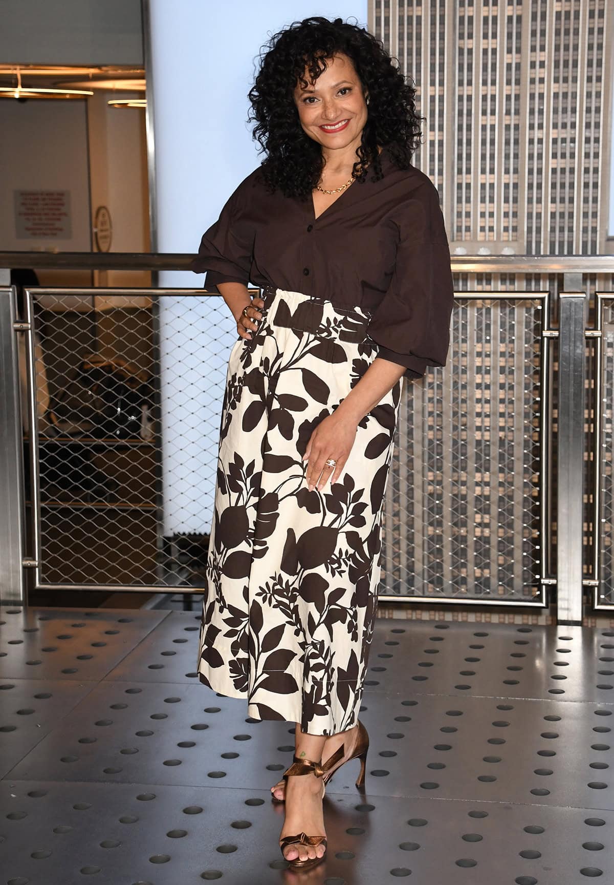 Judy Reyes pairs her brown Alexandre Birman sandals with the white-and-brown Brochu Walker “Edda” floral-print skirt and the brown “Kate” shirt with blouson sleeves and a scooped shirttail hem