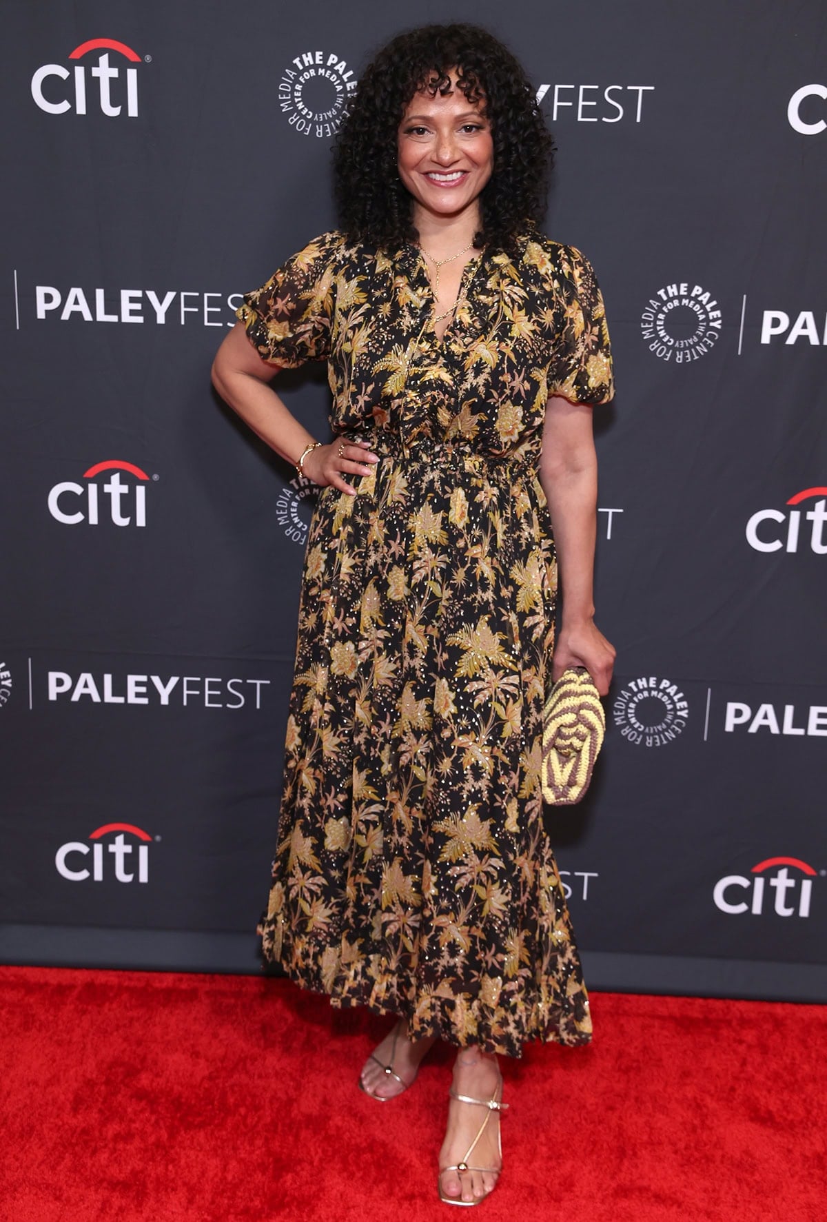 Judy Reyes pairs champagne metallic Loeffler Randall sandals with the Ulla Johnson “Rosamunde” chiffon dress, where gold botanical prints and a fluid silhouette echo the shoes’ warm shine and delicate, leg-lengthening lines
