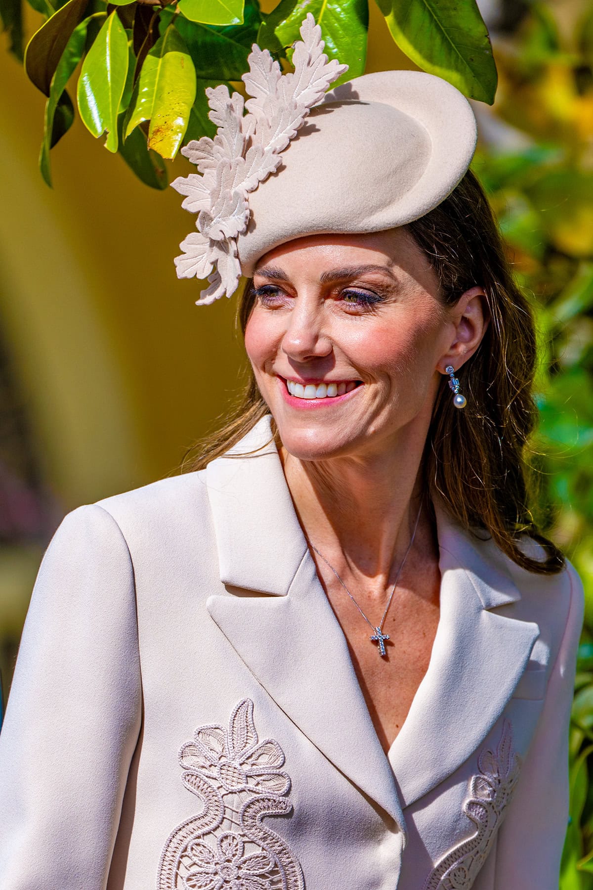 Kate Middleton styles her modest, elegant Easter Service look with a Juliette Botterill oak leaf teardrop hat, Bahrain Pearl Drop earrings from the Royal Collection, a dainty cross pendant necklace, and some rings