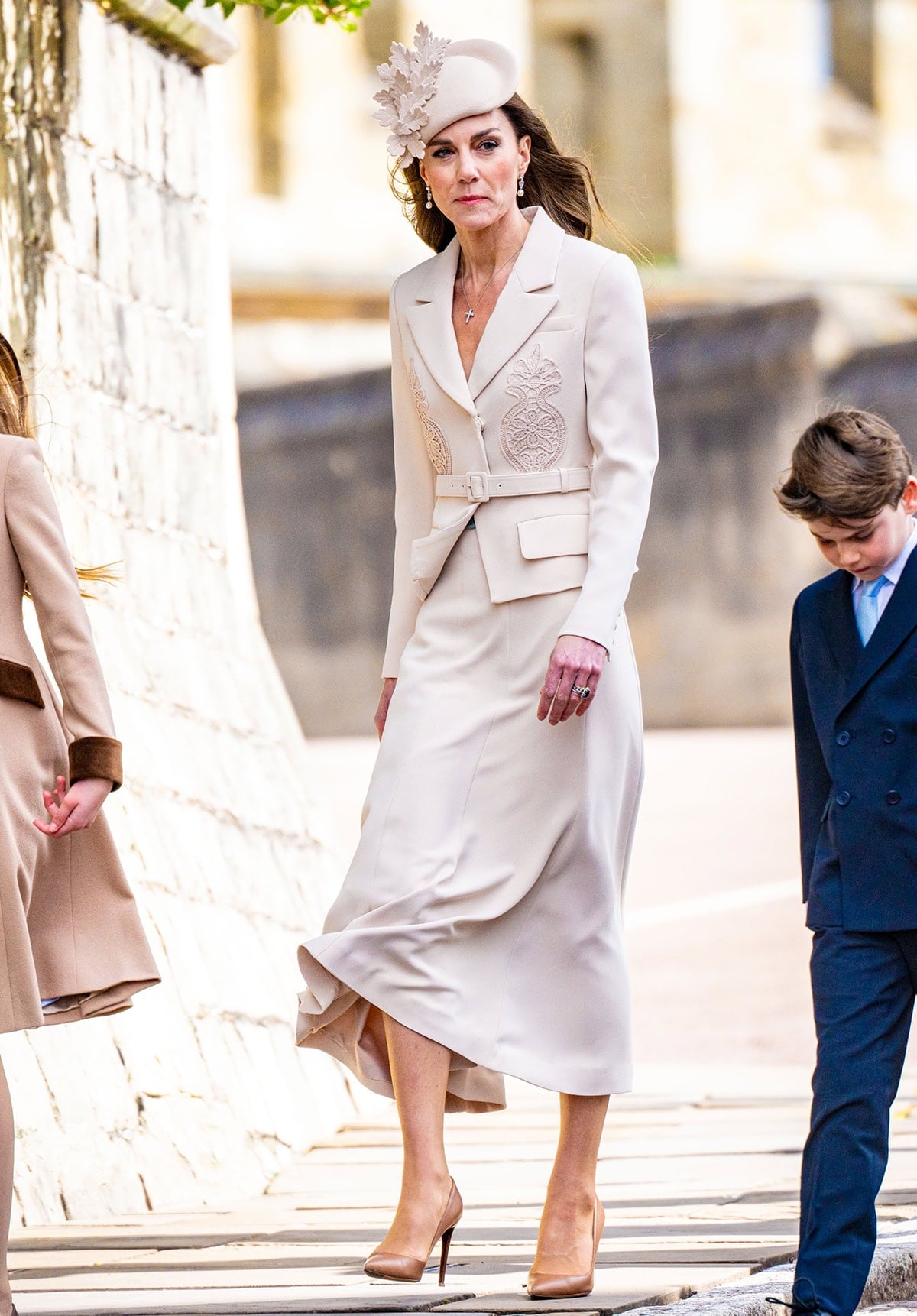 Catherine, Princess of Wales, pairs her brown pumps with a cream midi dress by Self-Portrait featuring floral embroidery, a blazer-style top, and a flowy midi skirt