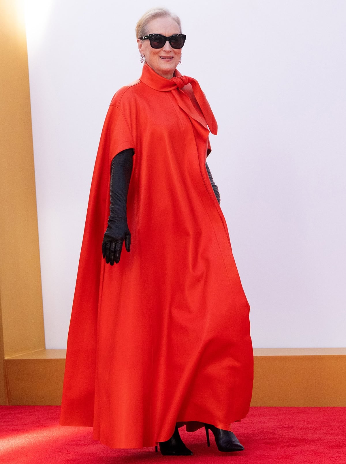 Meryl Streep teams her black boots with a dramatic red cape-style dress by Givenchy and black leather opera gloves
