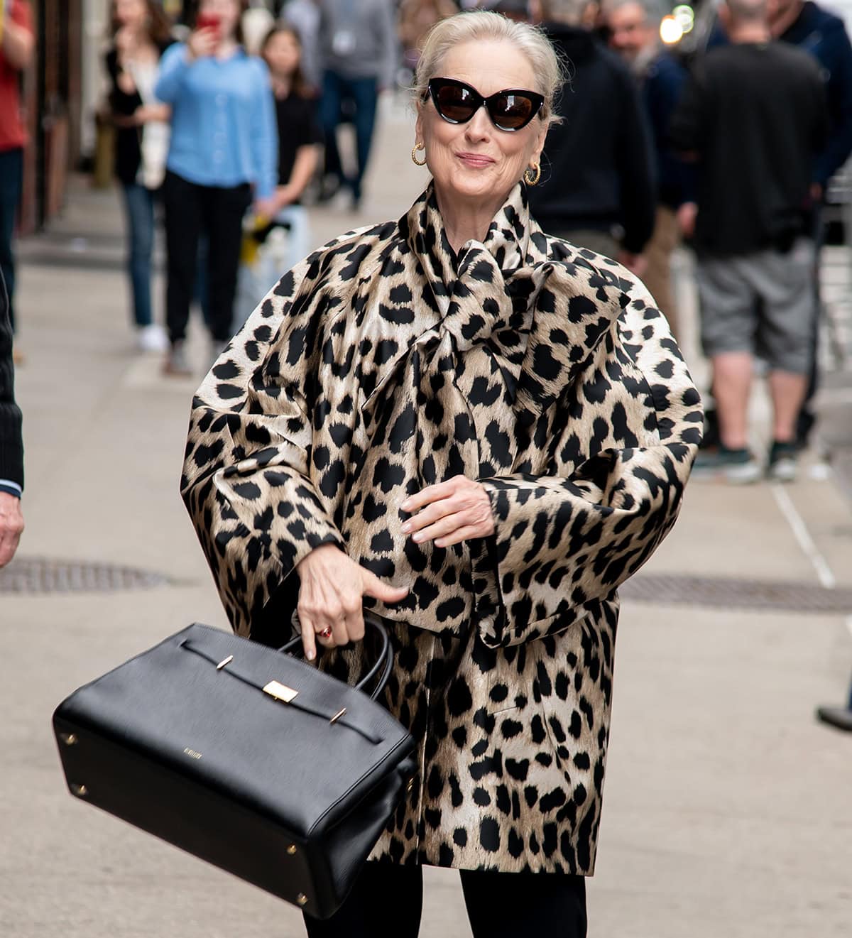 Meryl Streep styles her hair in a ponytail, accessorizes with Fope 1929 hoop earrings, and carries a structured black DeMellier bag