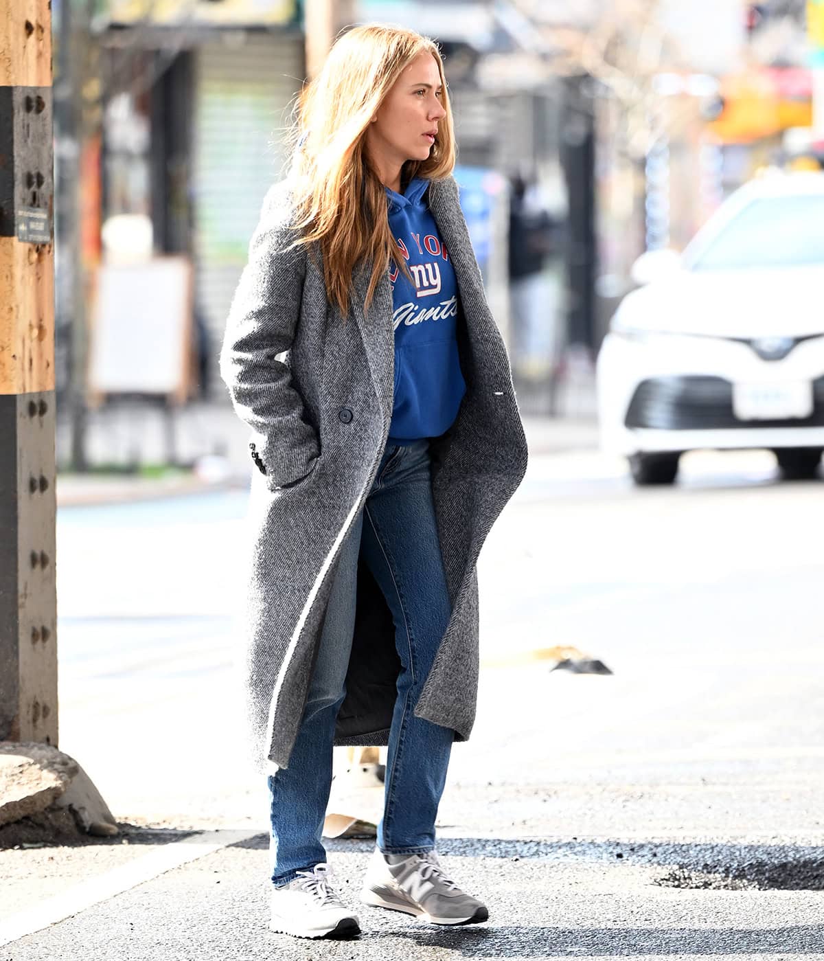 Scarlett Johansson pairs her New Balance sneakers with jeans, a blue New York Giants sweater, and a gray wool coat