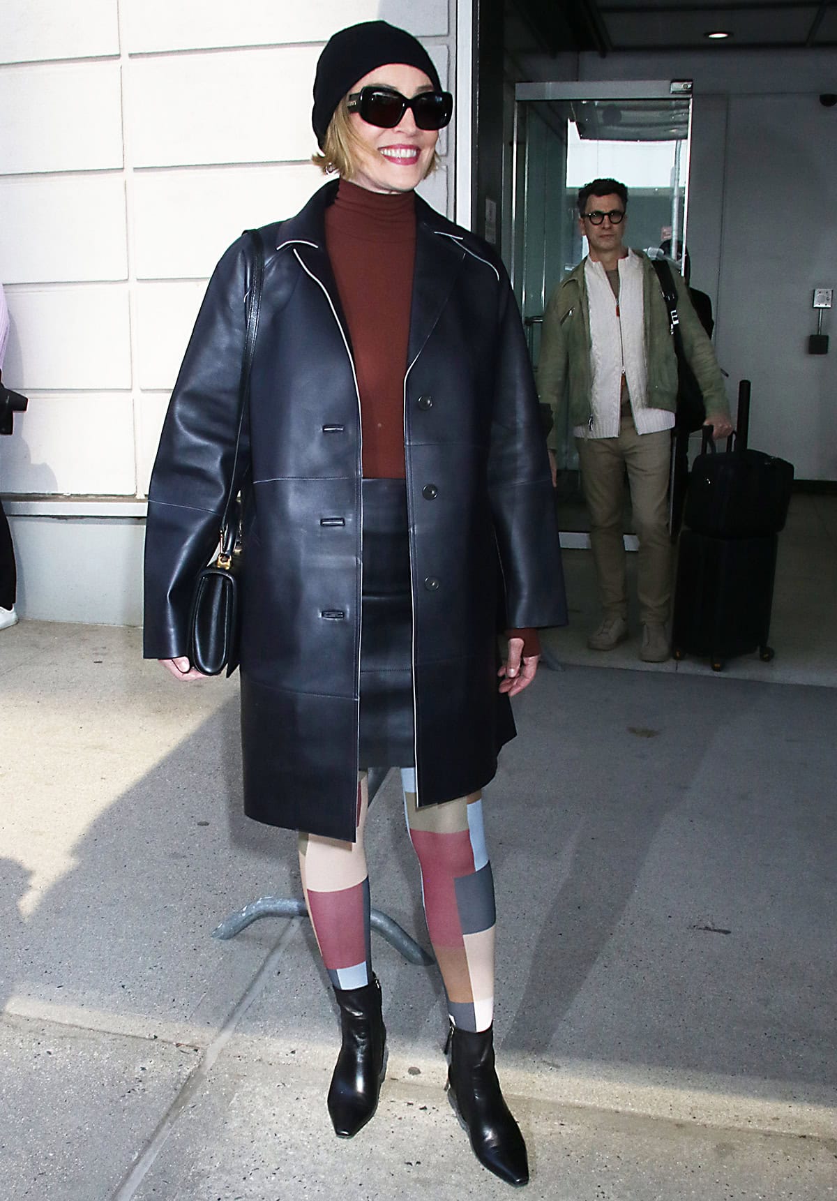 Sharon Stone drops by The Drew Barrymore Show in a bold outfit with a leather coat, mini skirt, colorful leggings, and ankle boots
