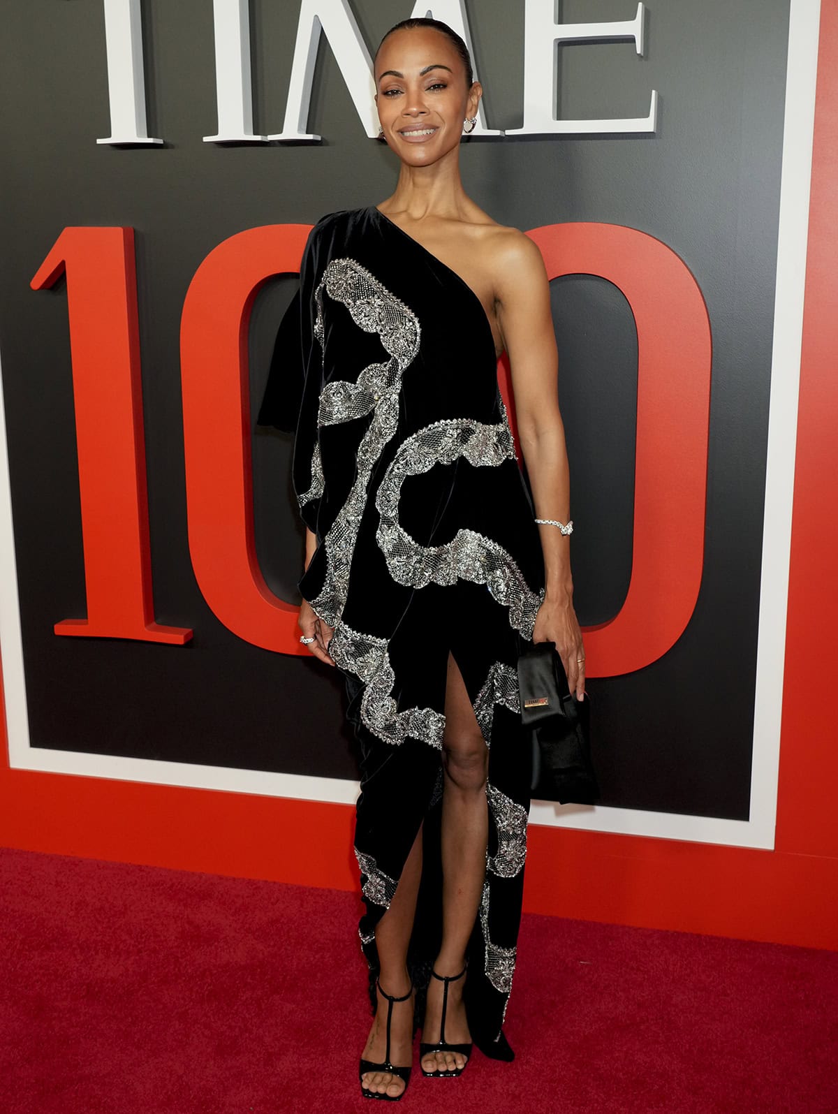 Zoe Saldaña pairs her open-toe T-strap heels with a black one-shoulder dress by Givenchy featuring crystal-encrusted ribbon embroideries