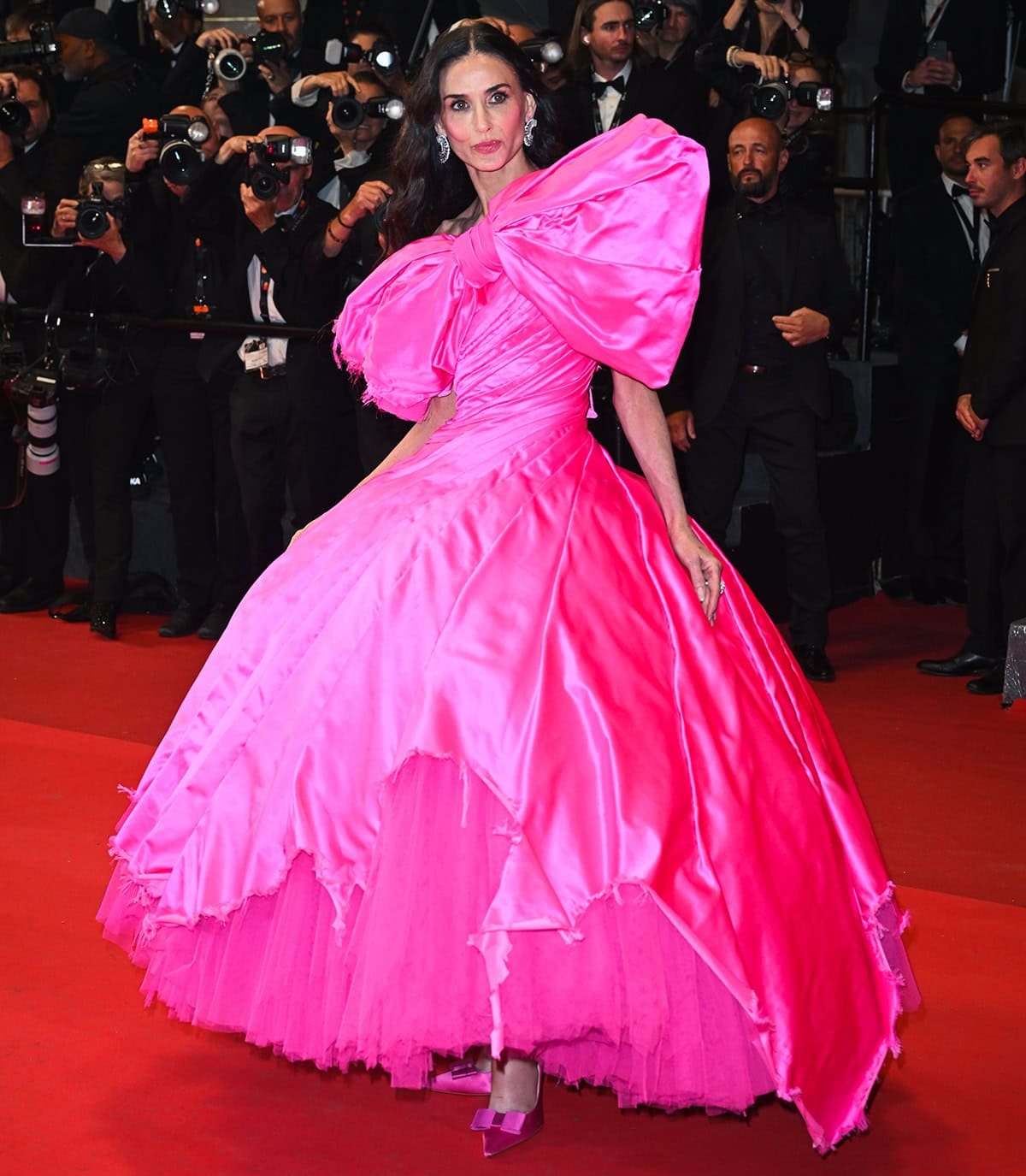 Demi Moore steals the spotlight in her hot pink Matières Fécales look, featuring a voluminous bow gown and matching pumps, at the 79th annual Cannes Film Festival premiere of Paper Tiger
