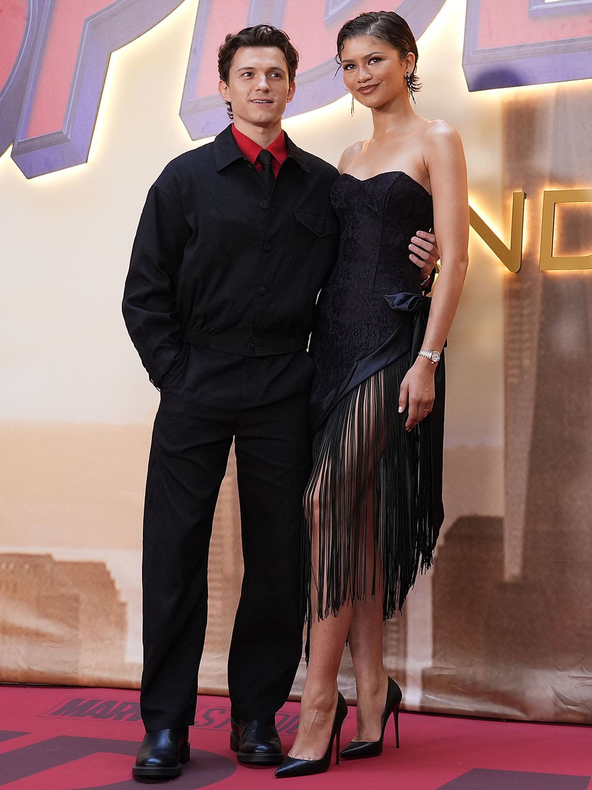 Tom Holland and Zendaya attend the Spider-Man: Brand New Day photocall at the Four Seasons Hotel in Madrid, Spain, on June 15, 2026, with Zendaya styling a fringed Christian Cowan corset dress and Christian Louboutin “So Kate” pumps while Holland complements her look in a tailored black Jacquemus ensemble accented by a Spider-Man-inspired red shirt collar